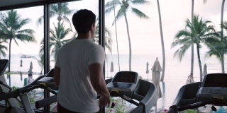 一名亚洲男子早上在度假健身中心的跑步机上锻炼。