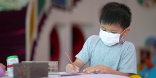 亚洲男孩在学校的美术课上画画