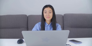 一名年轻的亚洲女性在封锁期间在家做自由职业。职业自由职业者女孩做远程在线工作。可爱的越南女性在笔记本电脑上输入4k股票视频