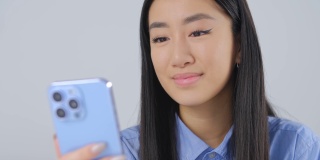 美丽的亚洲女孩打字短信在手机上。可爱的年轻越南女子使用现代智能手机进行在线交流和网络。来自亚洲的漂亮女性使用社交媒体应用程序