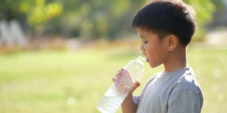 亚洲男孩在户外公园喝水