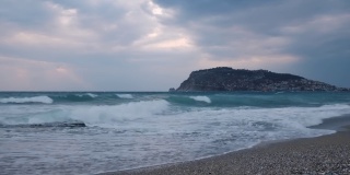 在海上风暴。海浪拍打着沙滩和卵石滩。美丽的海景度假城市阿兰亚，土耳其。神奇的自然景观