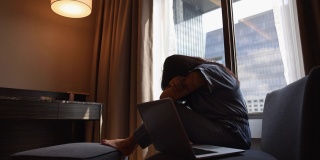 轮廓吸引人的亚洲女人从家里工作无聊的笔记本电脑。拖沓、疲惫的亚洲年轻女性在客厅用电脑做远程在线工作。监禁的冠状病毒。