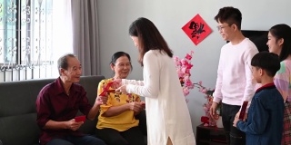 中国农历新年的第一天，亚洲老人在家里给他们的孩子和孙子孙女发红包。