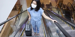 亚洲妇女戴医用口罩，以预防冠状病毒大流行传染病的爆发，并在公共区域乘坐自动扶梯。病毒大流行的概念