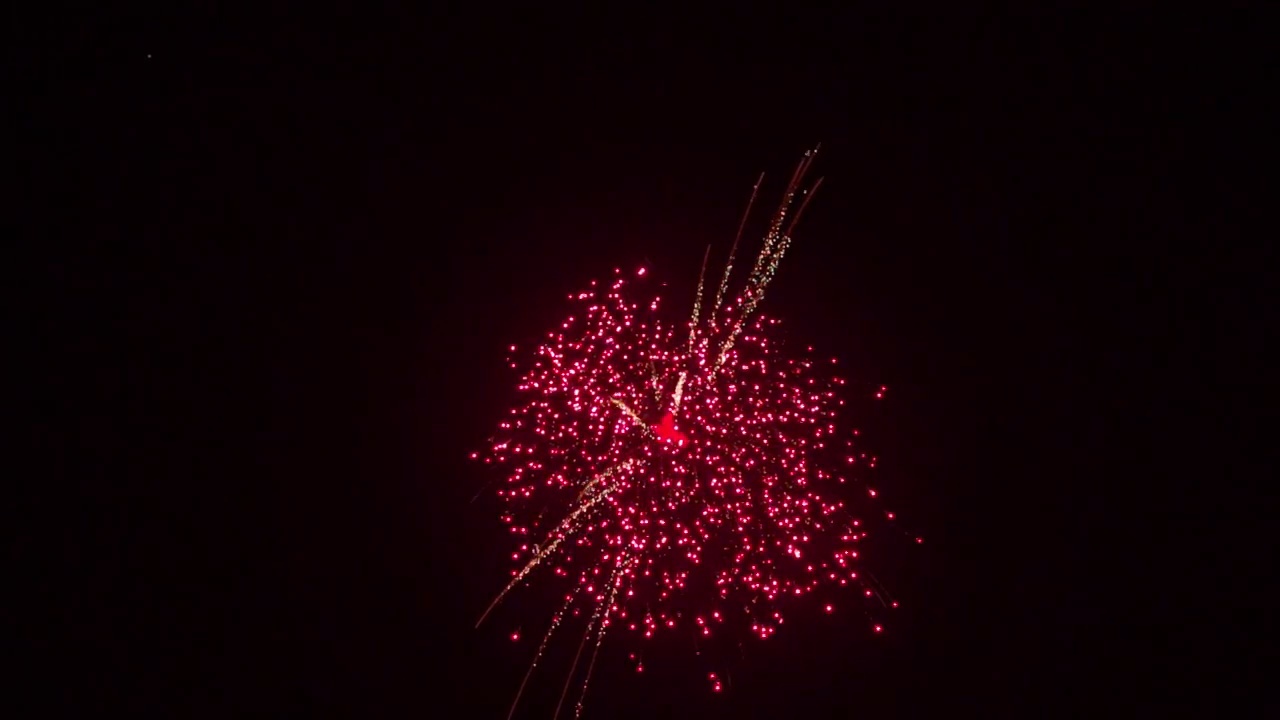 手持慢动作拍摄的天空射击爆竹爆炸反对黑色的天空在晚上。鞭炮在节日期间在天空中。烟花在天空背景庆祝节日。