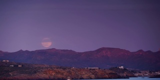 月亮在山上的海岸景色。间隔拍摄