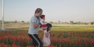 一个亚洲女人带着两个女儿在日落时分的向日葵农场。