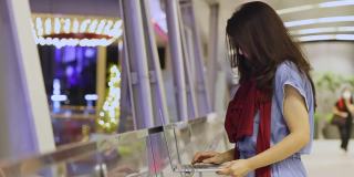 亚洲女商人在圣诞之夜用笔记本电脑做她的工作，背景是城市和装饰灯。