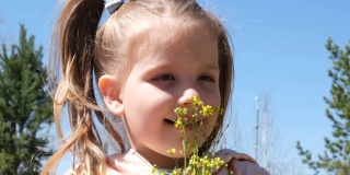快乐的孩子享受大自然的户外。春天。一个微笑的女孩闭着眼睛的肖像。美丽的白日梦小女孩捧着一束春天的黄花