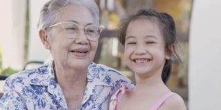 近4K户外的亚洲奶奶和孙女一起笑着，老女表达了对养老家庭的情感积极和幸福。