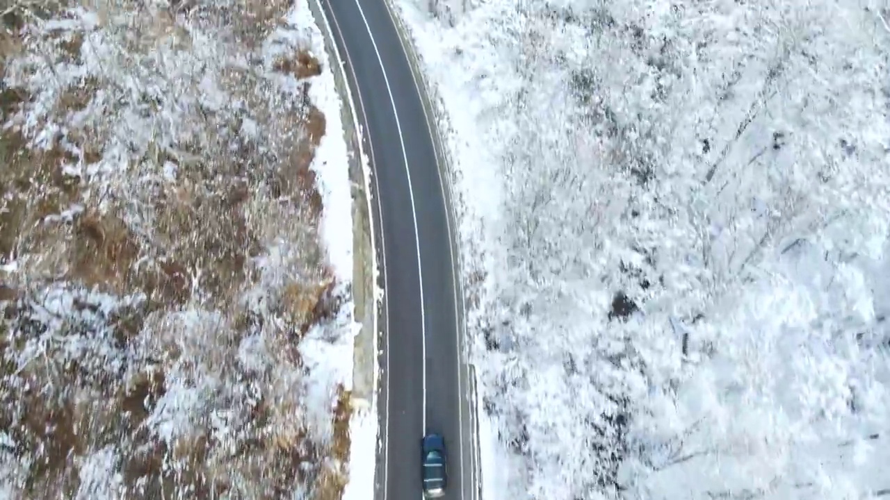 鸟瞰图的冬季道路与汽车和积雪覆盖的森林