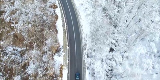 鸟瞰图的冬季道路与汽车和积雪覆盖的森林