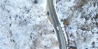 鸟瞰图的冬季道路与汽车和积雪覆盖的森林