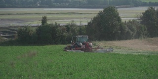 法国北部的农田上用拖拉机播种庄稼。法国布列塔尼地区的农业活动。拖拉机在田里耕作。种植和收获作物的过程。农业设备