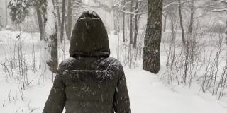 一个女孩在一个冬天的风雪过后，独自走在森林里被雪覆盖的小路上。4 k视频,60 fps。