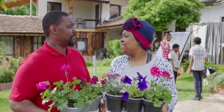 一对非洲裔美国夫妇拿着植物互相看着对方