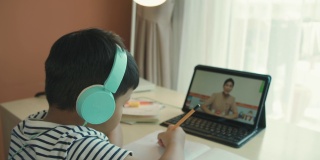一个亚洲男孩在家参加在线课程。
