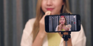 年轻的亚洲女性美妆博主用智能手机录制了化妆品教育教程视频，并在社交媒体(sns)上发布。