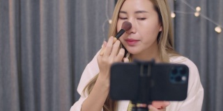 年轻美丽的亚洲女性美容博主，有影响力的化妆师，在智能手机上录制化妆品教育教程视频，适用于社交媒体的订阅者。