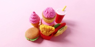 各种快餐特写的微缩模型。人类的手在明亮的粉红色背景上铺上美国快餐的小型玩具。4k延时搞笑微距视频。