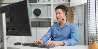 亚洲商人使用笔记本电脑视频电话与办公室同事。帅气的专业男员工坐在桌子上开会脑力激荡在公司的工作场所。