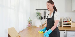 亚洲年轻清洁服务女工清洁厨房桌子在家里。年轻的女管家清洁工感到沮丧，而擦拭脏乱的烹饪柜台家务或杂务。