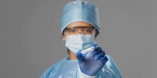 女性实验室研究人员穿着个人防护用品，拿着标有Covid 19的试管