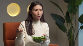 不开心的亚洲女性在节食，不喜欢吃健康的食物和蔬菜视频素材模板下载