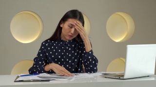 一名亚洲女性在办公室用手捂住脸，在办公桌上用笔记本电脑工作后，心情烦躁视频素材模板下载