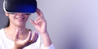 年轻女子在Metaverse体验VR时使用虚拟现实耳机触摸空气。VR(虚拟现实)，技术，视频游戏和元世界概念。
