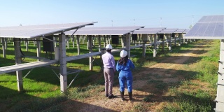 后视镜，高视镜:身穿蓝色防护服的亚洲中年工程师带着非洲投资者探索太阳能发电厂并讨论下一步计划