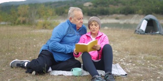 快乐的老年夫妇在树林露营时看书-老年人旅行的生活方式