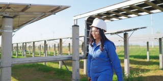 身穿蓝色防护服的亚洲中年工程师带着工具箱修理太阳能电池板，呼叫团队帮忙，太阳能电池板农场，侧视图