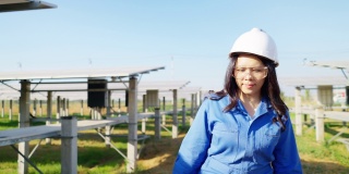 图片:亚洲中年工程师，蓝色防护服，带工具箱修理太阳能电池板，呼叫团队帮助，太阳能电池板农场，正面