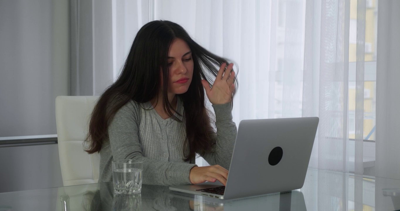 一名年轻女子坐在办公室的办公室里，用笔记本电脑在社交网络上浏览新闻。概念远程教育或自由职业
