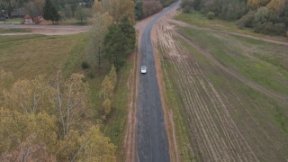 白色电动汽车在乡村道路上的鸟瞰图。现代汽车通过农村公路。视频素材模板下载