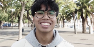 快乐的年轻亚洲人的肖像在户外的相机大笑