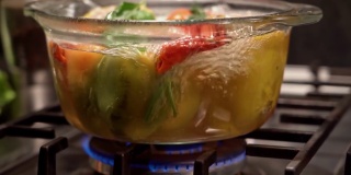 在烧开的水里煮填好的辣椒，放在炉子上一个透明的平底锅里，多利拍