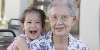 近4K户外的亚洲奶奶和孙女一起笑着，老女表达了对养老家庭的情感积极和幸福。