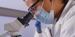 女性实验室工作人员或抽血师在实验室用显微镜分析血样的特写