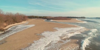 无人机拍摄的画面显示，冬天的时候，在有一条小河的沙滩上飞行