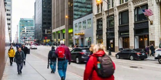 在美国伊利诺斯州芝加哥市，行人在高峰时间走在现代建筑之间的街道上