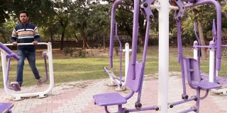 平移镜头，健力士步行者机，年轻人在公园户外健身步行者机上锻炼