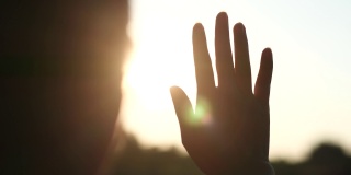 女人在阳光下伸展双手，在美丽的日落或日出的自然背景下。幸福的家庭的概念。