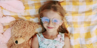 一个6-7岁的小女孩戴着眼镜，休息，用她的手问候