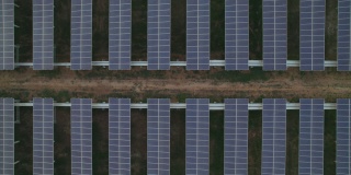 对称太阳能电池板农场的鸟瞰图，生产清洁的电力，中间有小的轨道