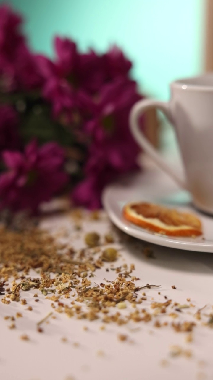 近距离观察桌子上的陶瓷茶杯，桌子上有草药，蜂蜜罐，鲜花