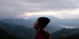 慢动作模糊的后视图，一个女性旅行者看着一个美丽的山景在雾天