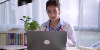 年轻漂亮的亚洲女医生在医务室，与病人进行在线会诊。年轻女医生用听诊器进行视频通话